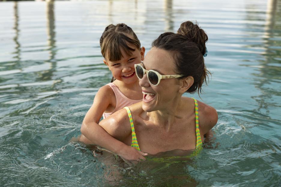 A mother and dauther playing in a swimming pool.