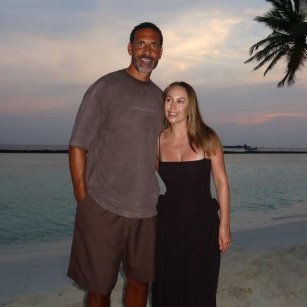 A man and woman standing on a beach at dusk.