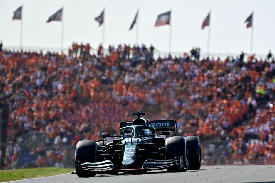Sebastian Vettel races his Aston Martin Formula One car on the Zandvoort circuit with a crowd of spectators in the background.