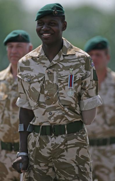 Ben McBean, a 21-year-old Marine wearing a green beret and camouflage, smiles while standing during a medal parade.