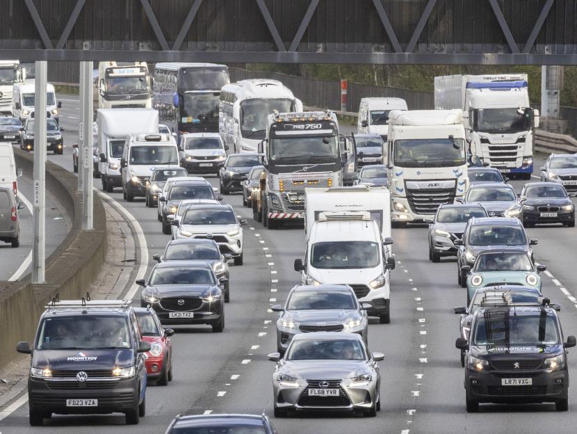 Heavy traffic with cars, vans, and trucks on the M25 in Egham, UK.