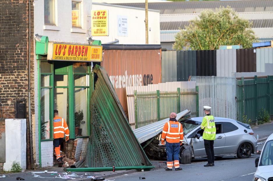 Emergency services at the scene of a serious road collision in Tipton, West Midlands, where a silver car has crashed into a takeaway restaurant.