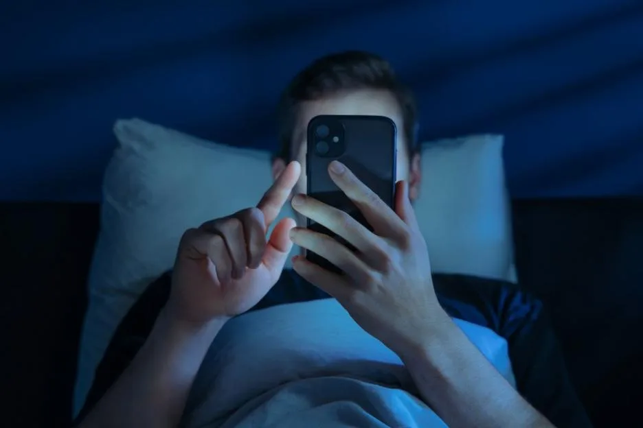 Man holds his smartphone close to face while brousing social media at night