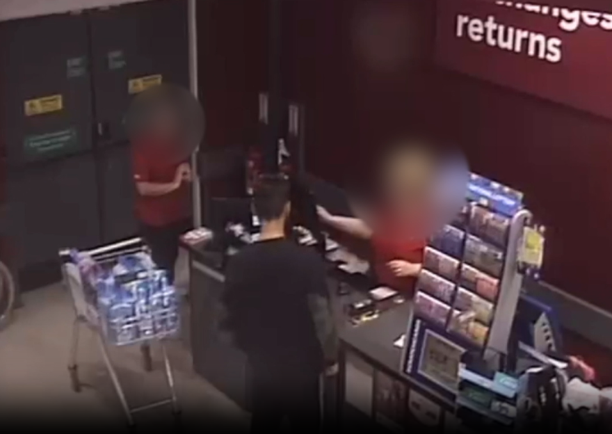 CCTV footage showing two individuals, blurred for anonymity, at a store checkout, with a shopping cart full of bottled water nearby.
