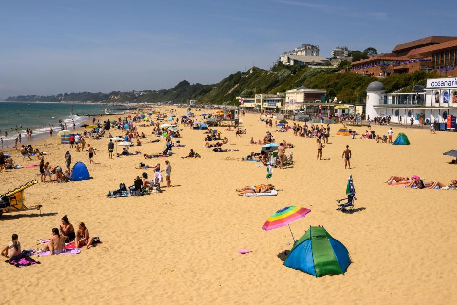 Beachgoers enjoying a hot day at the beach in Bournemouth, England.