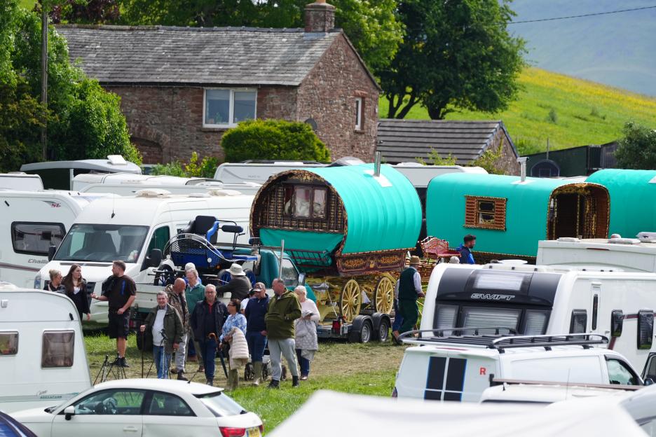 People gathered at the Appleby Horse Fair with traditional horse-drawn caravans and modern trailers.