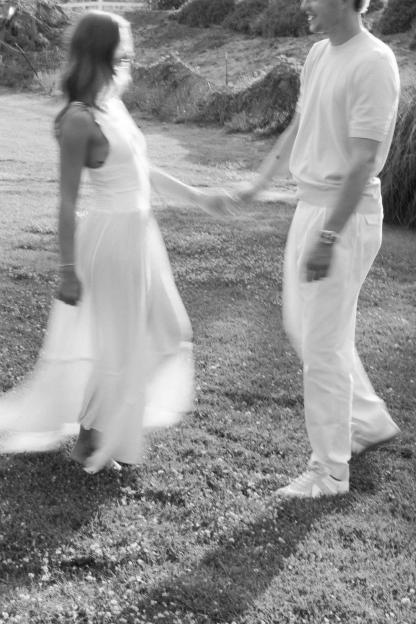 Blurry black and white photo of an engaged couple holding hands outdoors.