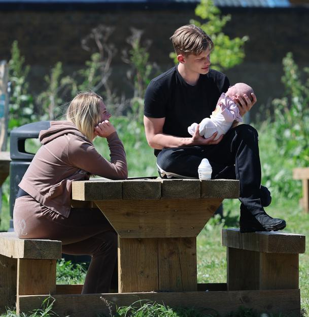 Freddy Brazier holding his baby daughter Isla with Holly Swinburn in a park.