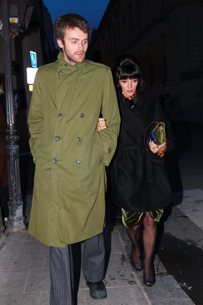 Lily Allen in a black coat and Jonah Freud in a green coat making a stylish appearance in Paris.