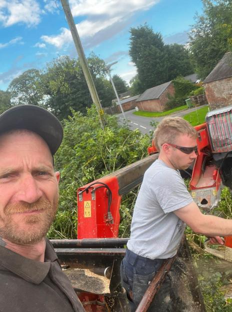Two men using a wood chipper.