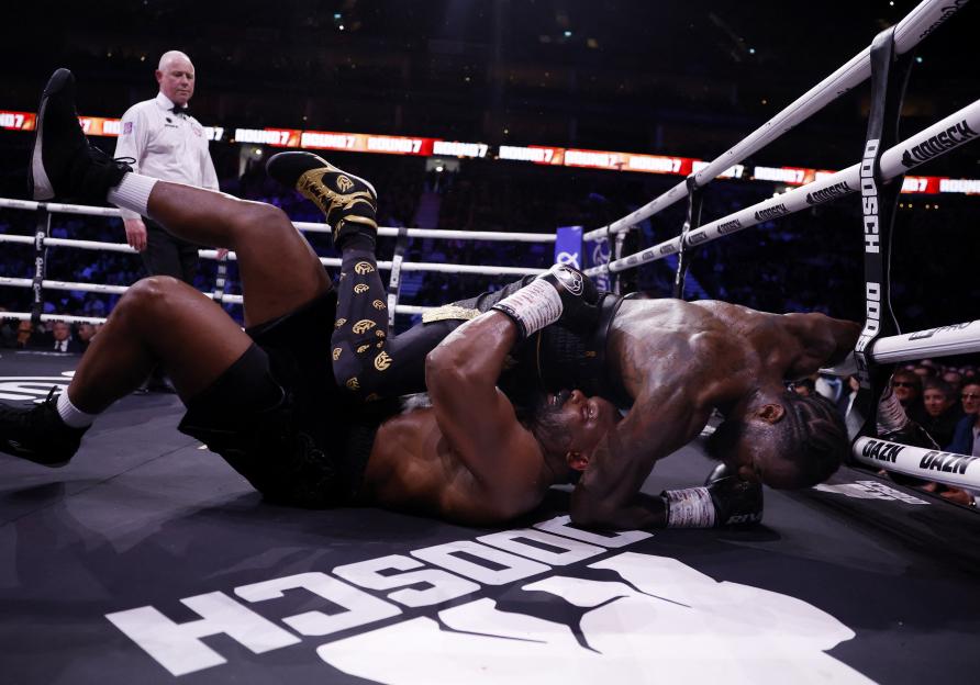 Boxers Derek Chisora and Deontay Wilder fall during their fight.