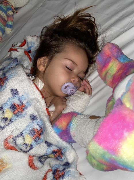 A young child, Primrose Hocking, sleeping with a pacifier and covered by a blanket.