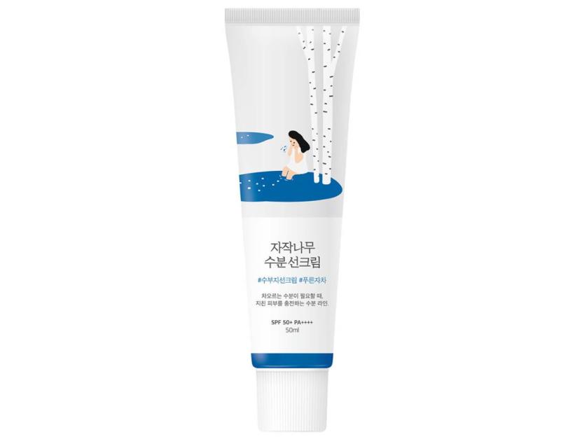 A tube of Round Lab sun cream with a birch tree and a person sitting by a lake illustration on the front.