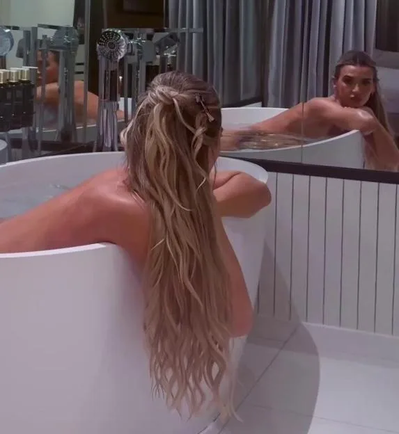 Christine McGuinness in a bathtub, viewed from behind with her reflection in a mirror.