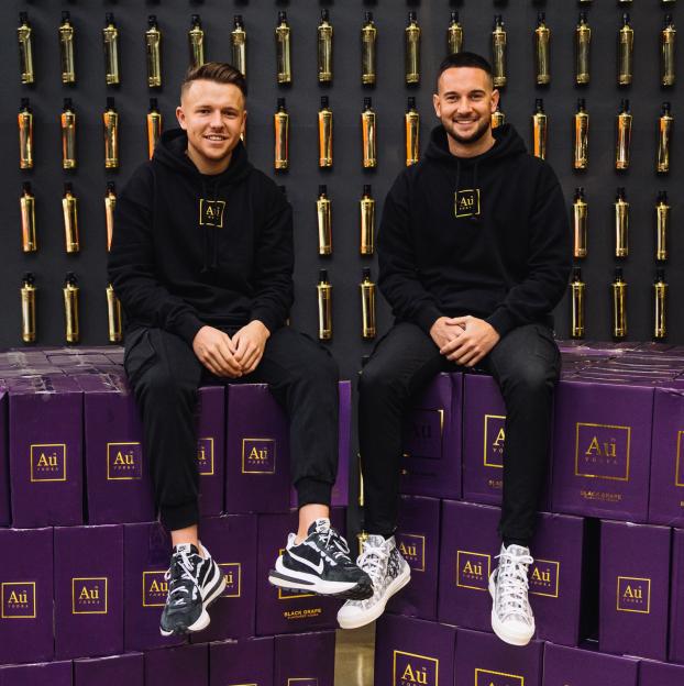 Two men sitting on boxes of Au Vodka.