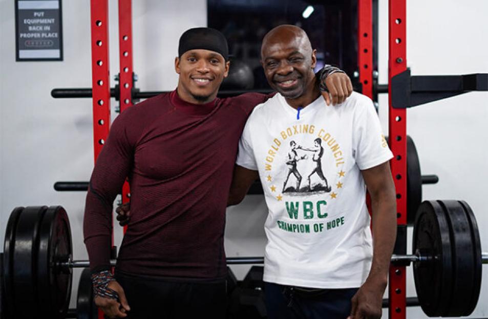 Anthony Yarde and Tunde Ajayi smiling while posing together in a gym.