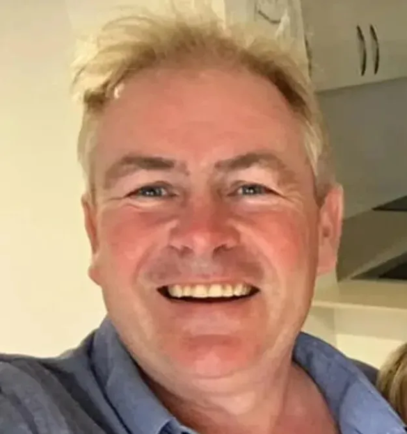 Headshot of a man with blonde hair and blue eyes, smiling.