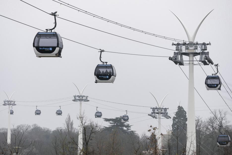 The C1 urban cable car system in Île-de-France during its official launch, with multiple gondolas suspended on cables between tall white support poles.