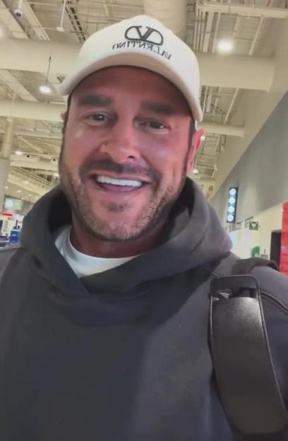 Man in a white cap and black hoodie smiling