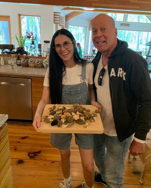 Demi Moore and Bruce Willis smiling and holding a tray of morel mushrooms.