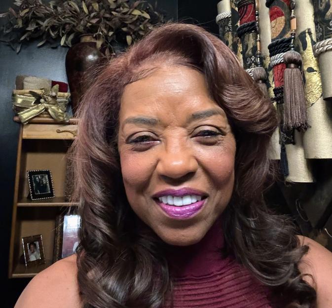 A smiling woman with brown hair and purple lipstick.