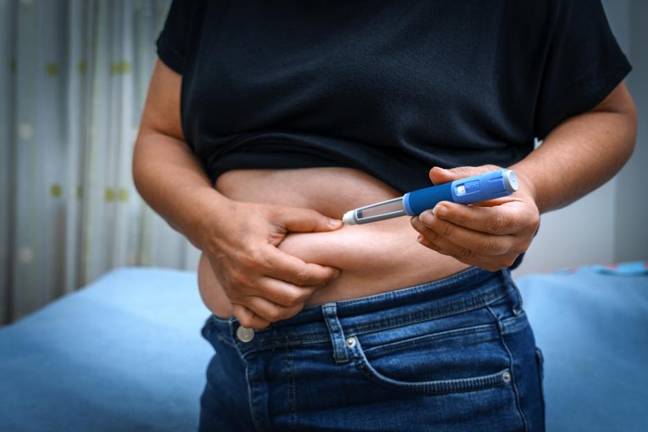 Person injecting insulin into their stomach for diabetes management.