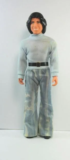 A vintage John Travolta fashion doll wearing a light blue turtleneck and flared trousers.