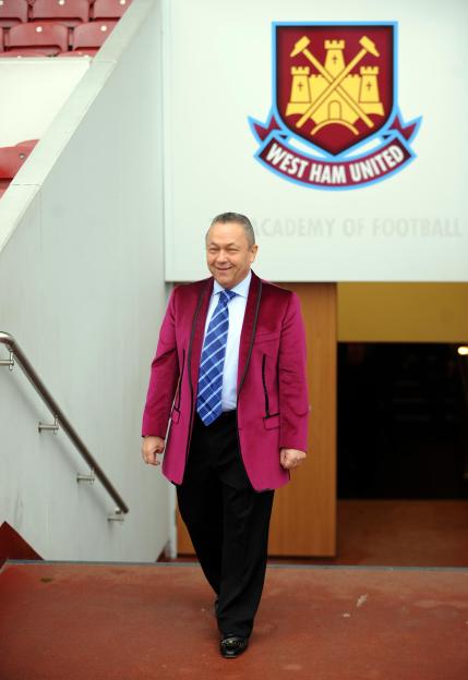 David Sullivan smiling as he descends stairs with the West Ham United logo visible in the background.