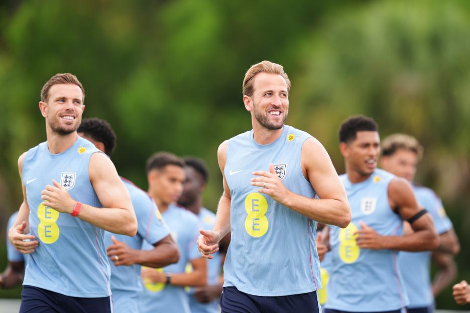 Harry Kane and Jordan Henderson jogging with teammates during national soccer team training.