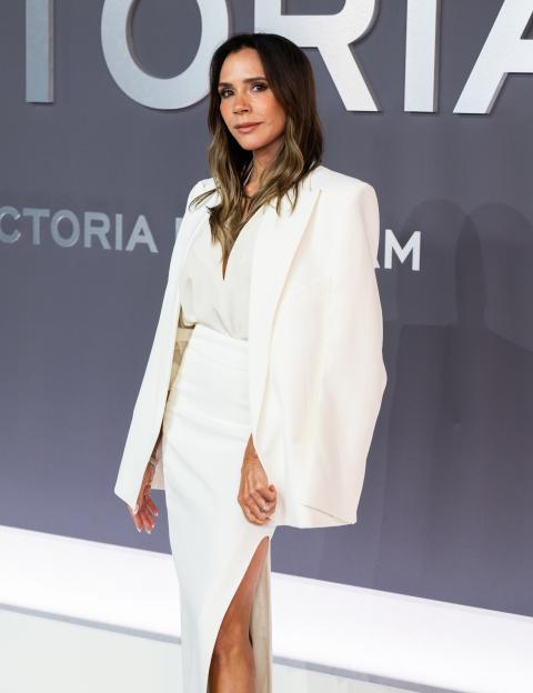 Victoria Beckham posing at the "Victoria Beckham" World Premiere in a white top, blazer, and high-waisted skirt.