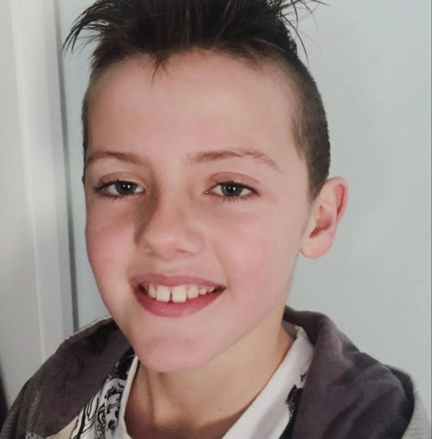 Jeremy, a boy with short dark hair, smiling while wearing a white shirt under a gray hoodie.