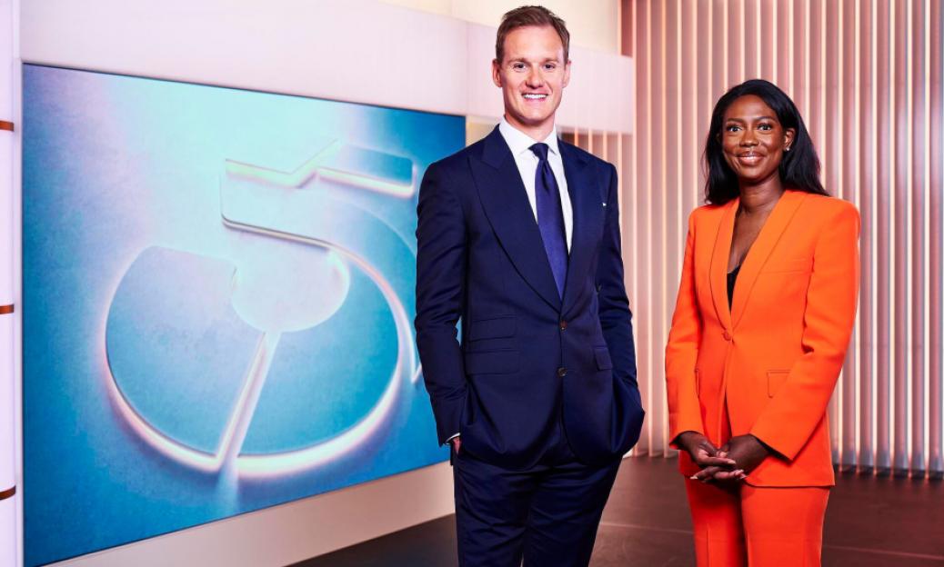 Dan Walker and Claudia-Liza Vanderpuije standing in front of a blue background with a large white number 5.