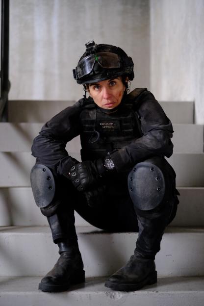 Vicky McClure as Lana Washington in the TV series "Trigger Point" sits on stairs, wearing a tactical helmet and vest.