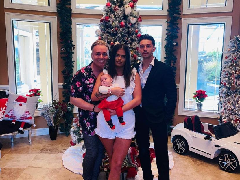 Barrie Drewitt-Barlow, Saffron Drewitt-Barlow, and Scott Hutchinson with baby Valentina in front of a Christmas tree and a toy Bentley car.