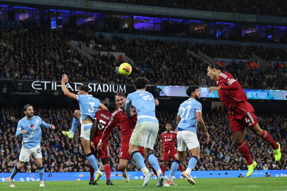 Virgil van Dijk heading the ball during a soccer match against Manchester City.