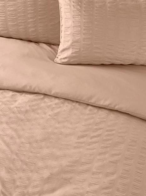 Close-up of peach-colored bedding with a subtle striped texture.