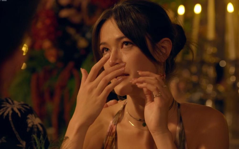 A woman with dark hair wipes tears from her face.