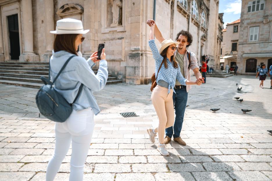Woman filming a couple dancing in an old town square.