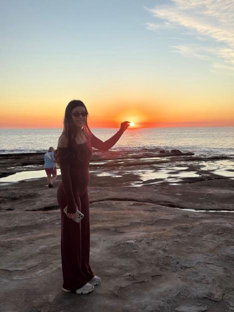 Yana Marks posing with the sunset on a rocky beach.