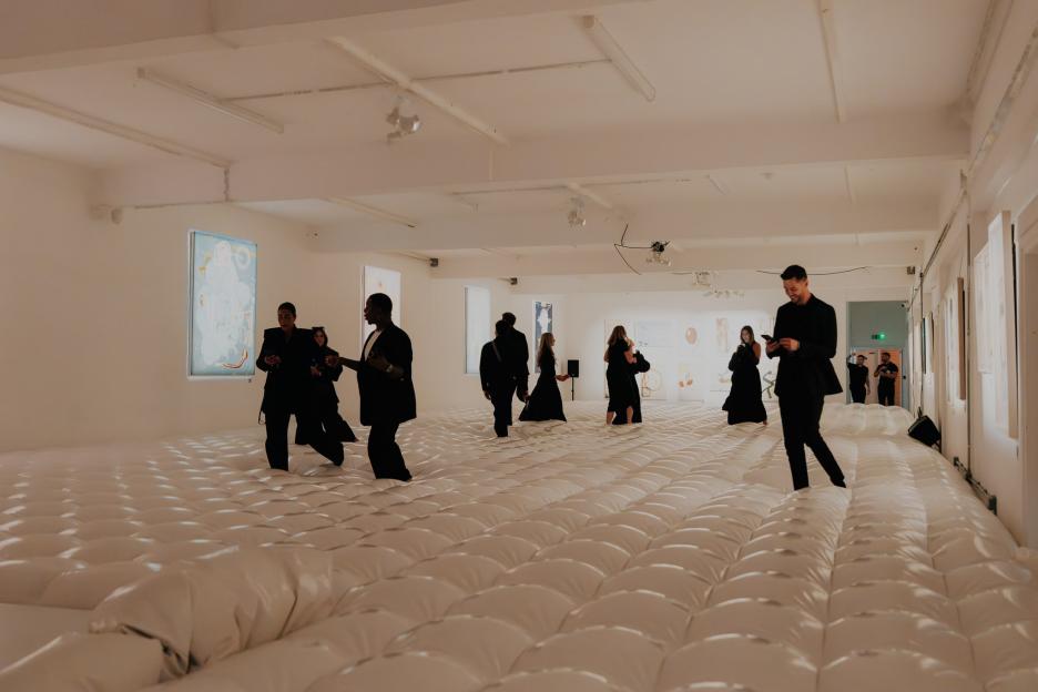 Attendees walking on a bouncy, white inflatable floor at Jake Hall's memorial exhibition.