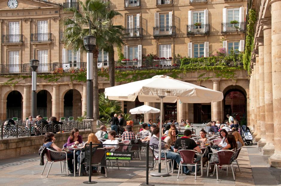 People dining al fresco at an outdoor restaurant in Plaza Nueva, Bilbao, Spain.