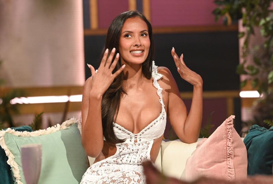 Maya Jama posing in a white laced dress on the set of Love Island Aftersun.