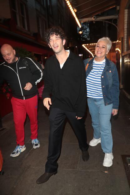 Matty Healy and his mother, Denise Welch, exiting a building at night.