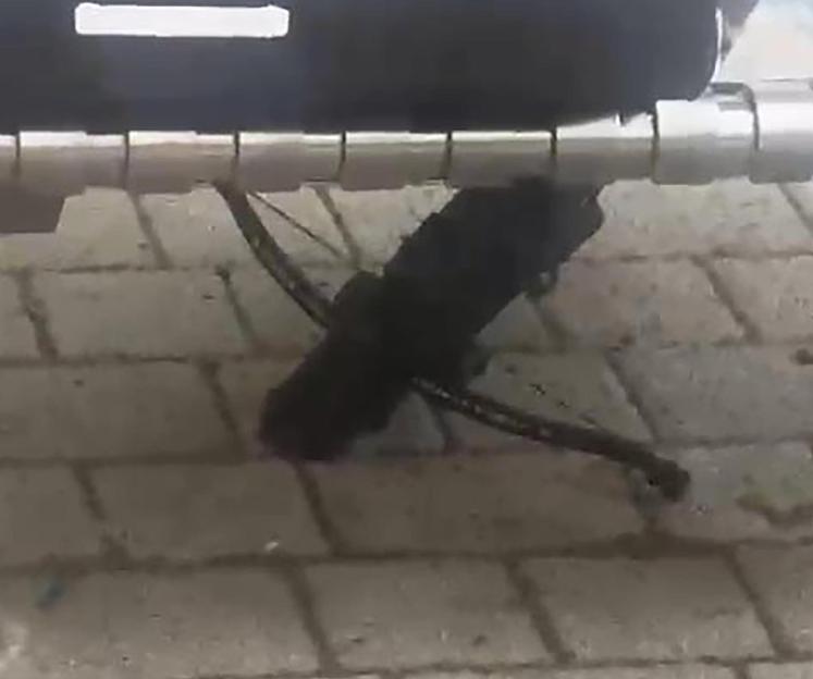 A black crossbow resting on gray pavement.