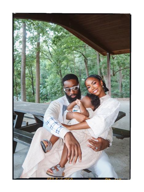 Aïssata Diallo and her partner pose with their baby son outdoors.