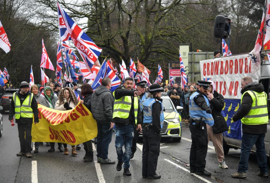 People protesting in Crowborough, UK, with signs saying "Crowborough Says No" and Union Jack flags.
