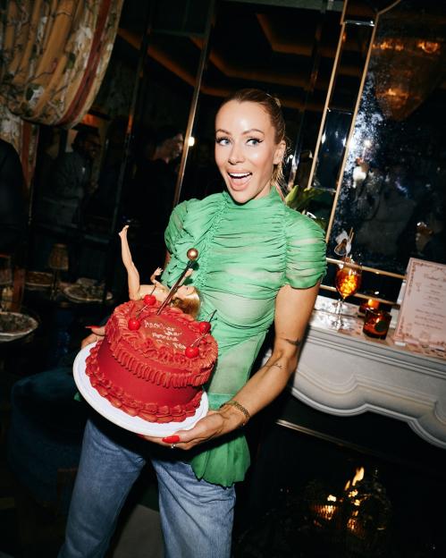 Olivia Attwood holding a red birthday cake with a Barbie doll and cherries.