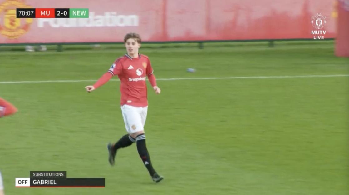 A soccer player in a red jersey and white shorts running on a green field.