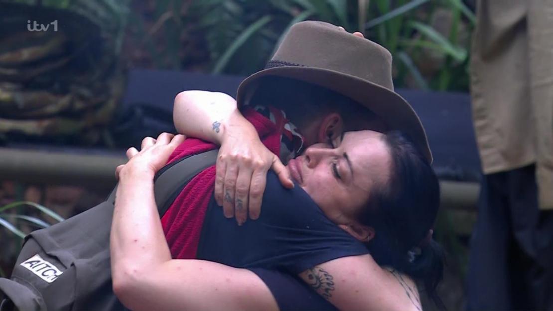 Two people hugging, one wearing a hat.