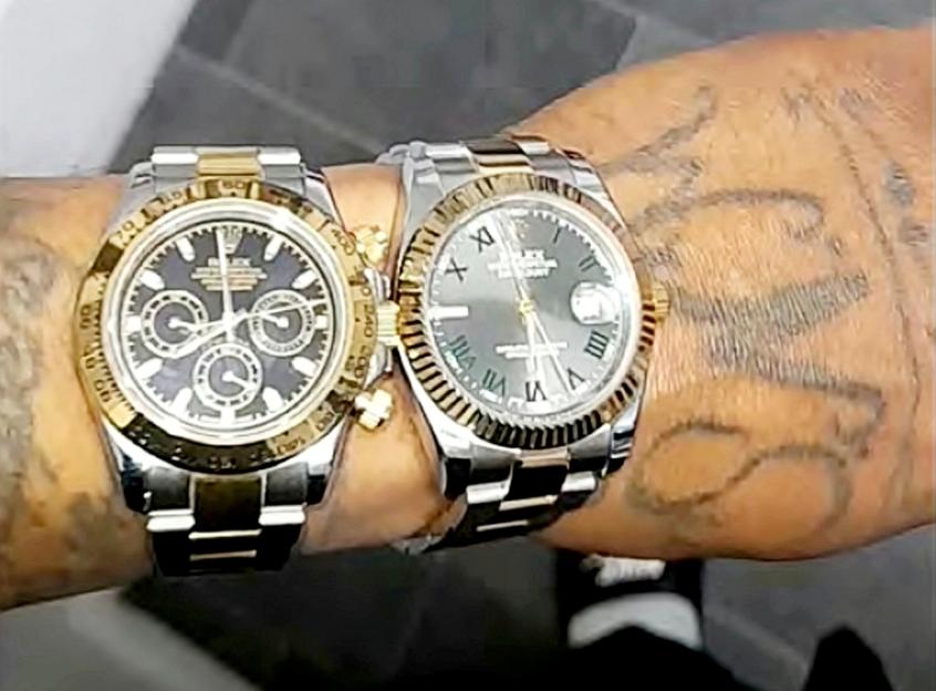 Two Rolex watches on a tattooed wrist.